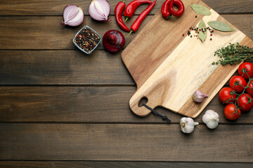 Cutting board and vegetables on wooden table, flat lay with space for text. Cooking utensil