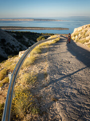Riding a bicycle up a hill called Kamenjak on island of Rab