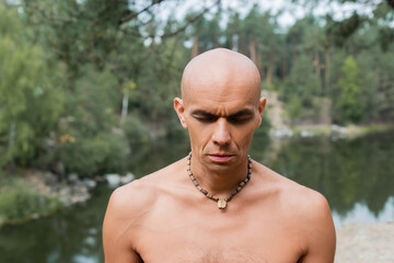 Fototapeta na wymiar shirtless buddhist in beads meditating with closed eyes in forest