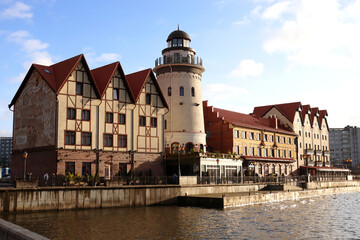Naklejka premium View of the Rybnaya village and the Pregolya river in Kaliningrad. There are cafes, hotels and a large white lighthouse on the embankment.