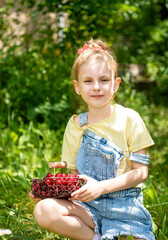 Little girl is picking cherries in the garden.