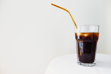 Glass of ice coffee with metal straw and white background