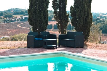 Outdoor sofas under cypress trees near the pool (Umbria, Italy, Europe) - 458536371