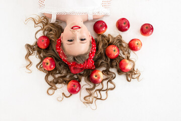 curly-haired girl's face and scattered red apples