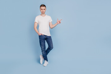 Photo of young man point finger empty space promo suggest recommend isolated over blue color background