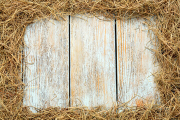 Frame of dried hay on light wooden background, flat lay. Space for text