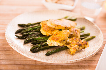fried chicken breast pieces with asparagus on white plate
