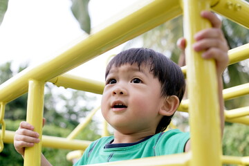 Fototapeta premium little boy climb up the ladder on the playground : close up