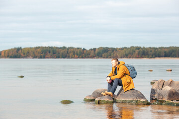 Caucasian man sitting on the rock in front of lake and enjoying the view. Man resting after a long...