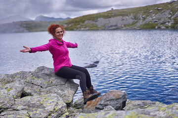 Naklejka na ściany i meble Happy woman resting after hiking by a lake