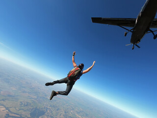 Fototapeta na wymiar Skydiver jumps from a black plane on a hot day with clear skies.