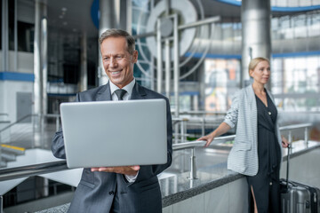 Smiling business man looking at laptop and colleague