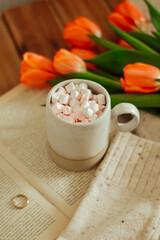 drink with marshmallow and tullips and book on wooden background