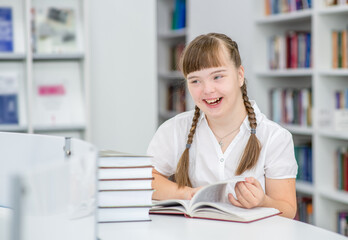 Happy young girl with syndrome down at library.  Education for disabled children concept