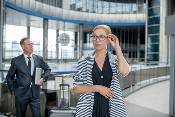 Serious business woman with glasses and colleague behind