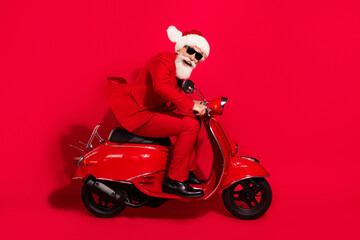 Photo of charming funky mature motorcyclist dressed christmas costume hat smiling hurrying isolated red color background