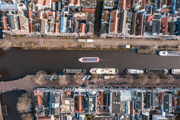 Fototapeta na wymiar Canal Boat Passing Between Waterfront Houses in Amsterdam Bird's Eye View
