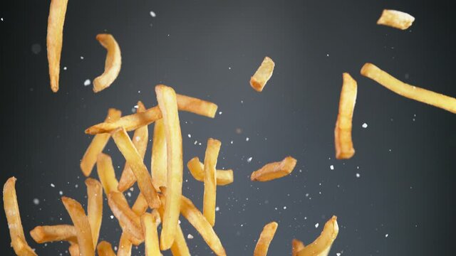 Super slow motion of flying french fries on black background. Speed ramp effect. Filmed on high speed cinema camera, 1000 fps.
