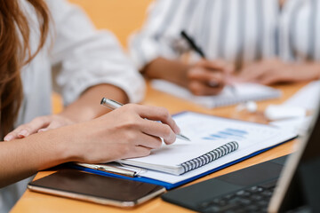 Close-up of a businesswoman  hand holding a pen and taking notes report of work at the meeting room.