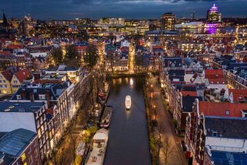 Naklejka premium Amsterdam City Canals at Night with a Tour Boat Aerial View