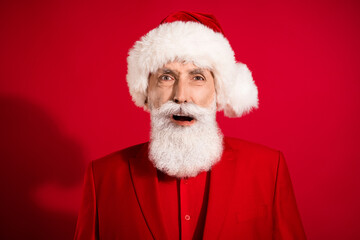 Photo of shocked speechless santa claus open mouth wtf grimace wear x-mas hat tuxedo on red color background