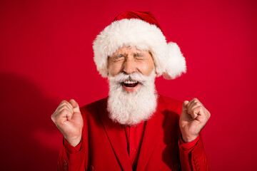 Photo of happy cheerful old man christmas santa claus hat winner celebrate isolated on red color background