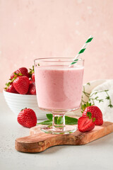 Two strawberry smoothie or milkshake with berries and mint in glass on light pink background. Summer drink shake, milkshake and refreshment organic concept. Healthy dieting, vegetarian food concept.