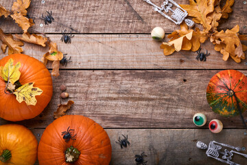 Halloween Pumpkin. Festive autumn decor from pumpkins, leaves, spider, skeletons and funny eyes on old wooden background. Flat lay autumn composition with copy space.
