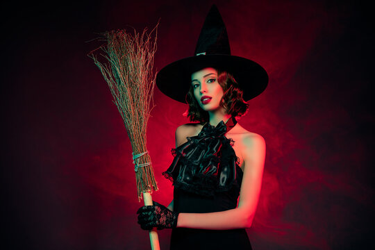 Photo of seductive tempting mystical woman wear sexy witch dress headwear holding broomstick isolated dark red color background - Powered by Adobe