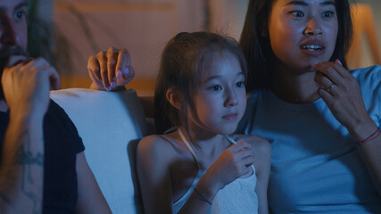Girl watching film with parents