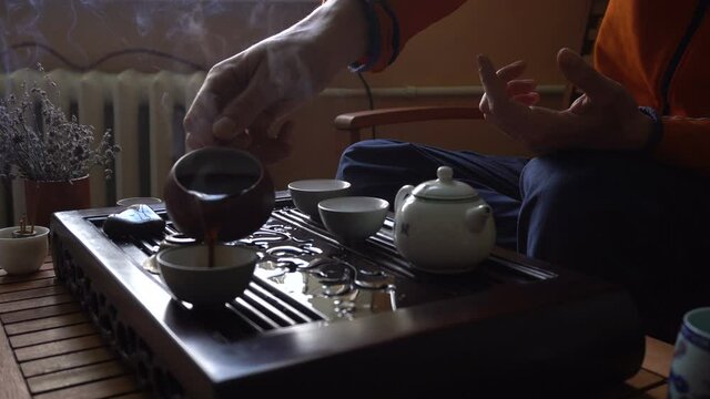 man pouring puer tea in teapot at traditional chinese tea ceremony set of equipment