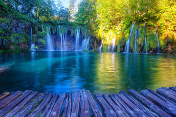 Waterfall in sunny day on Plitvice Lakes. Boardwalk on foreground