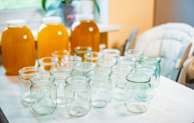 Composition of a large number of jars and three jars of honey standing on a white table against a background of light