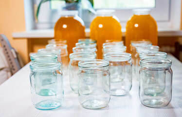 Composition of a large number of jars and three jars of honey standing on a white table against a background of light