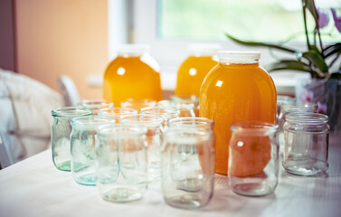Composition of a large number of jars and three jars of honey standing on a white table against a background of light