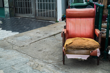 Old red upholstered chair that is not being used that was abandoned beside a pile of rubbish. Copy space.