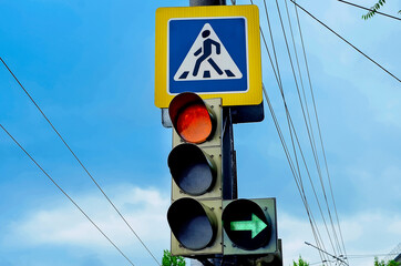 Traffic lights over urban intersection. Red light and green arrow. Pedestrian crossing sign.