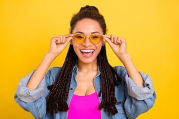 Photo of young excited afro girl happy positive smile hands touch sunglass isolated over yellow color background