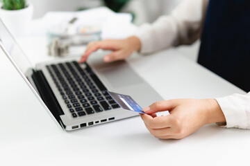 Woman spending money on Online shopping. Hands holding credit card and using laptop working at home e-commerce and internet banking concept
