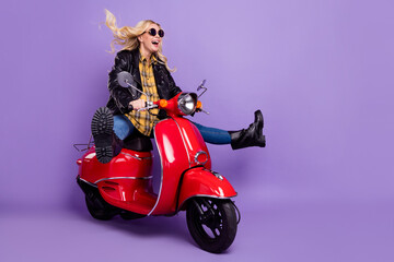 Portrait of attractive comic cheerful wavy-haired girl riding moped fooling isolated over bright violet purple color background © deagreez