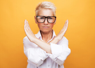 elderly woman with short gray hair wearing casual style rejection expression crossing arms doing...