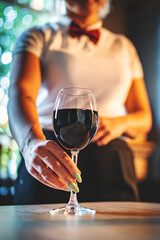 waiter hold red wine into a glass in cafe or bar