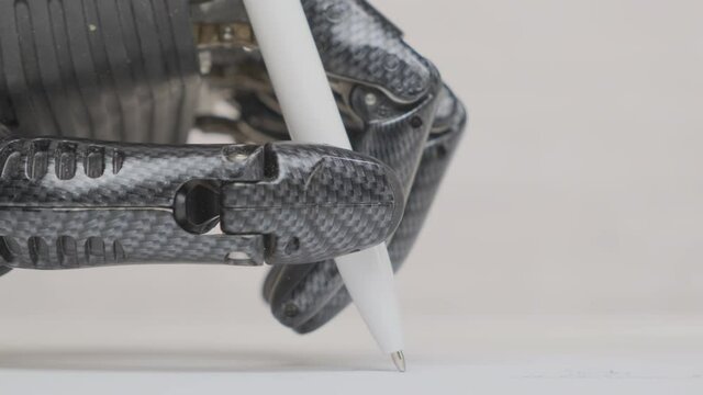 Man with bionic prosthetic hand writes pen on paper sheet close up.