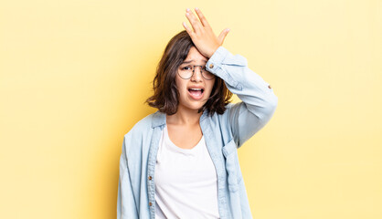 young pretty girl raising palm to forehead thinking oops, after making a stupid mistake or...