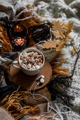 Cocoa with marshmallows, a cozy blanket, headphones on the bed. Autumn home cozy still life, top view