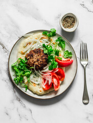 Unleavened flatbread with burger, yogurt sauce, fresh tomatoes and cilantro on a light background, top view