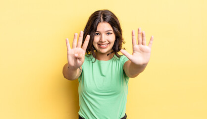 young pretty girl smiling and looking friendly, showing number nine or ninth with hand forward,...