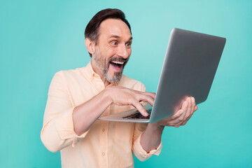 Photo of mature happy cheerful handsome businessman working in laptop computer isolated on teal color background