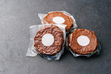 Raw vegan meatless cutlets in vacuum film, hamburger on a dark background. Mockup sticker