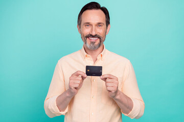 Photo of smiling cheerful handsome male hold demonstrate credit debit card isolated on bright turquoise color background